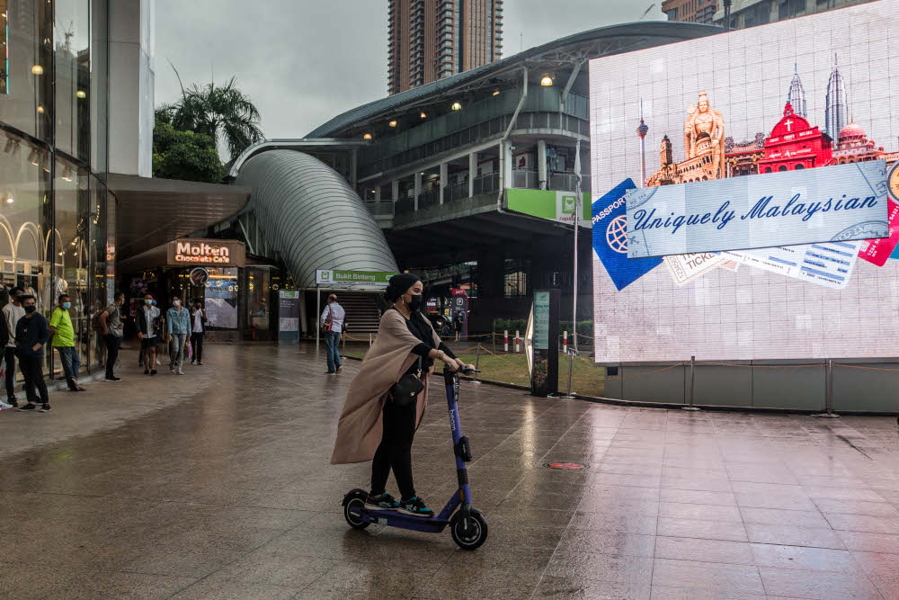 A woman wearing a protective face mask rides an electric scooter in Bukit Bintang, Kuala Lumpur January 3, 2021. u00e2u20acu201d Picture by Firdaus Latif