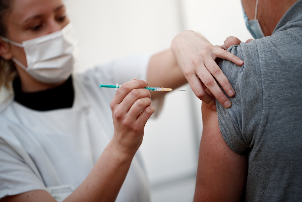 A healthcare worker receives a dose of the Pfizer-BioNTech Covid-19 vaccine at a coronavirus disease vaccination center inside a gymnasium in Taverny near Paris, France, January 9, 2021. u00e2u20acu201d Reuters picnn