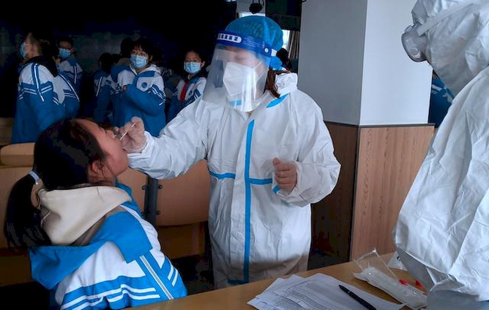 A medical worker in a protective suit collects a swab sample from a middle school student during a testing following a recent coronavirus disease (Covid-19) outbreak in Xingtai, Hebei province, China January 6, 2021. u00e2u20acu201d China Daily pic via Reuters