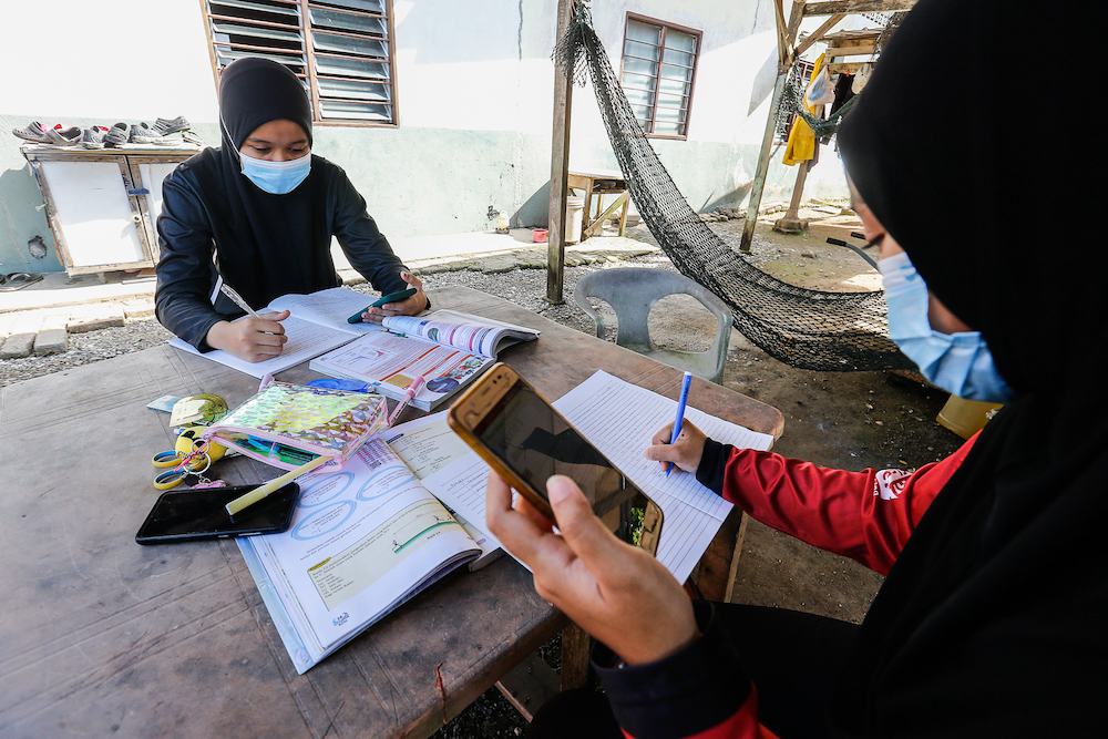 Nur Alea Soffiyyah Ahmad Hanif (left) and her schoolmate Hanis Syuhada Razali (right) attend online classes in front of their house on Pulau Aman January 22, 2021. u00e2u20acu201d Picture by Sayuti Zainudin