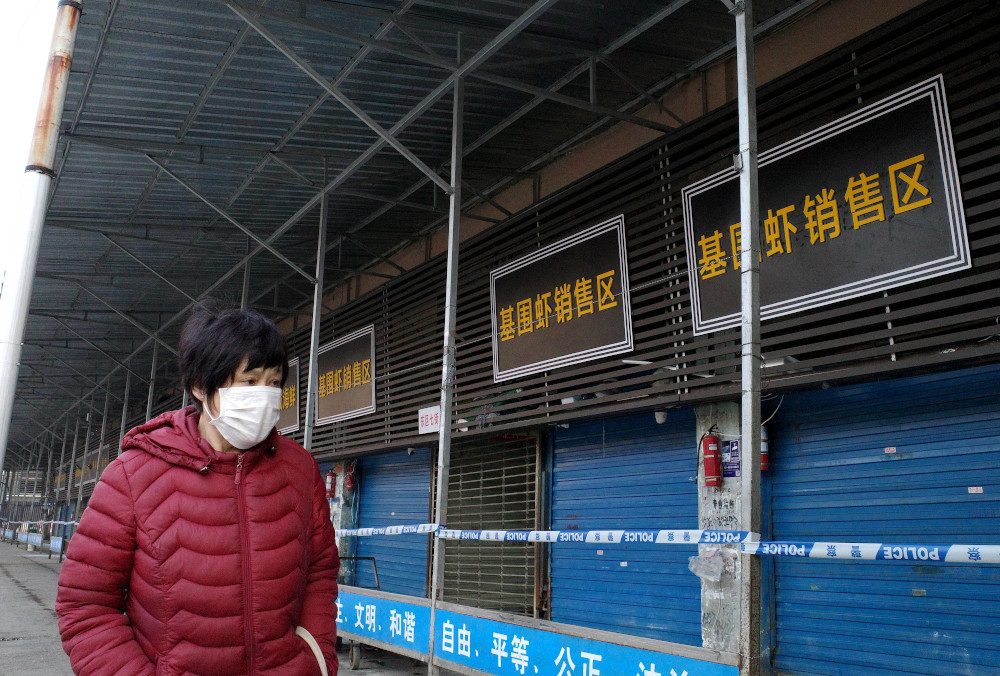 This file photo taken January 12, 2020 shows a woman walking in front of the closed Huanan wholesale seafood market, where health authorities say a man who died from a respiratory illness had purchased goods from, in Wuhan, Hubei province. u00e2u20acu201d AFP pic 