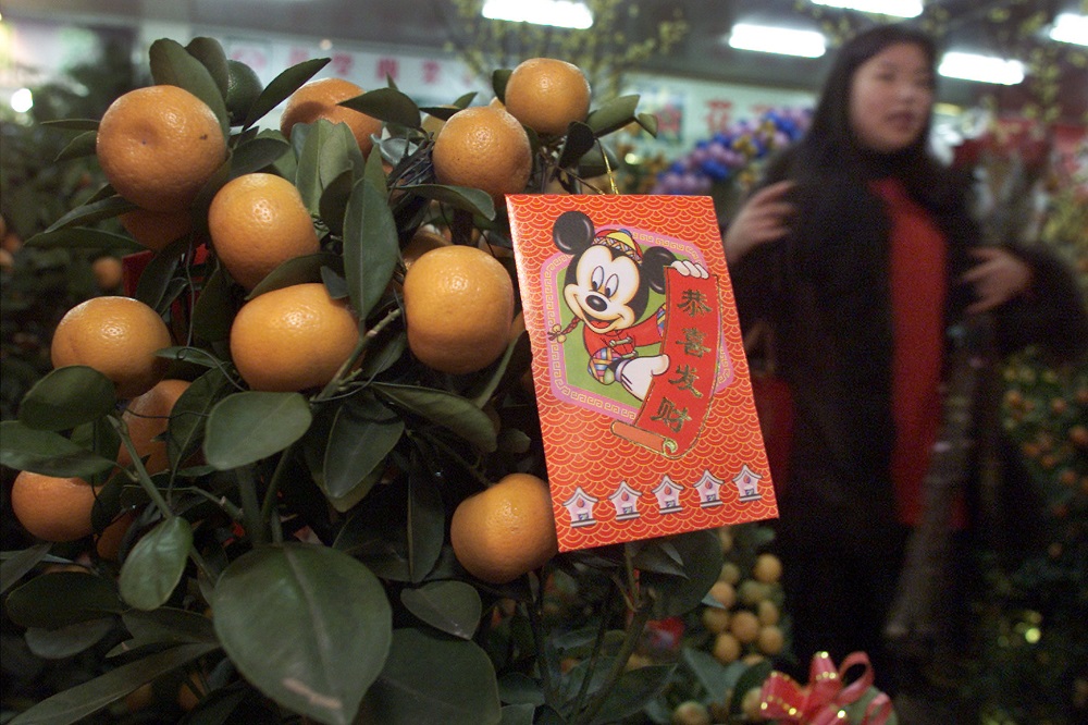 A Chinese shopper passes a kumquat plant with a Mickey Mouse red packet inscribed with u00e2u20acu02dcHave a Prosperous New Yearu00e2u20acu2122 at a flower market in Shanghai, China's financial capital January 31, 2003. u00e2u20acu201d Reuters pic