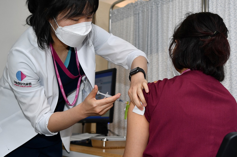 A medical worker (right) receives the first dose of the Pfizer BioNTech vaccine Covid-19 at the National Medical Centre vaccination centre in Seoul February 27, 2021. u00e2u20acu201dPool pic via Reuters