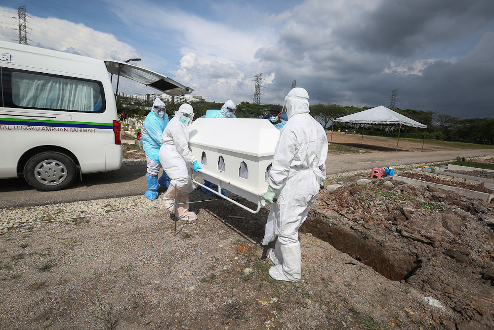 Workers wearing personal protective equipment (PPE) carry the body of a Covid-19 victim at a cemetery in Shah Alam February 11, 2021. u00e2u20acu201d Picture by Yusof Mat Isa