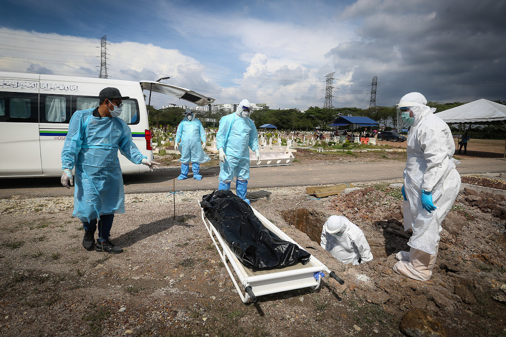 Workers wearing personal protective equipment bury the body of a Covid-19 victim at a cemetery in Shah Alam February 11, 2021. — Picture by Yusof Mat Isa