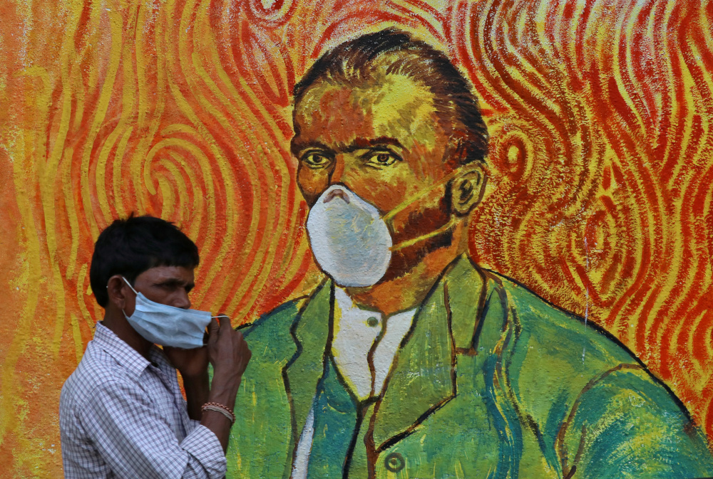 A man adjusts his face mask as he walks past a mural, amidst the spread of the coronavirus disease in Mumbai, India, March 11, 2021. u00e2u20acu201d Reuters picnn