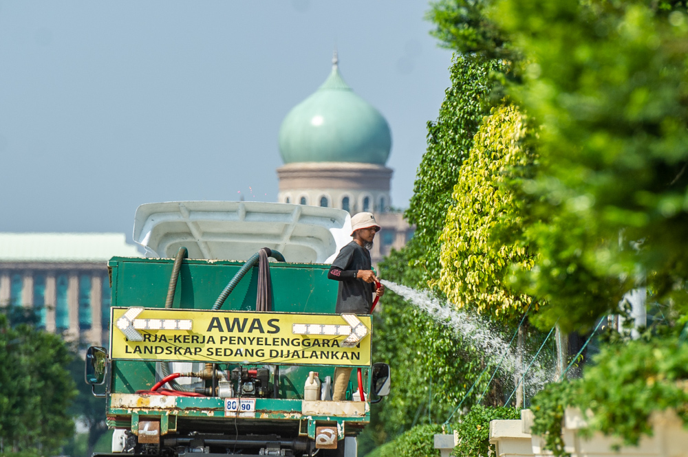 A landscape worker is seen watering plants at Putrajaya Boulevard February 18, 2021. — Picture by Shafwan Zaidon