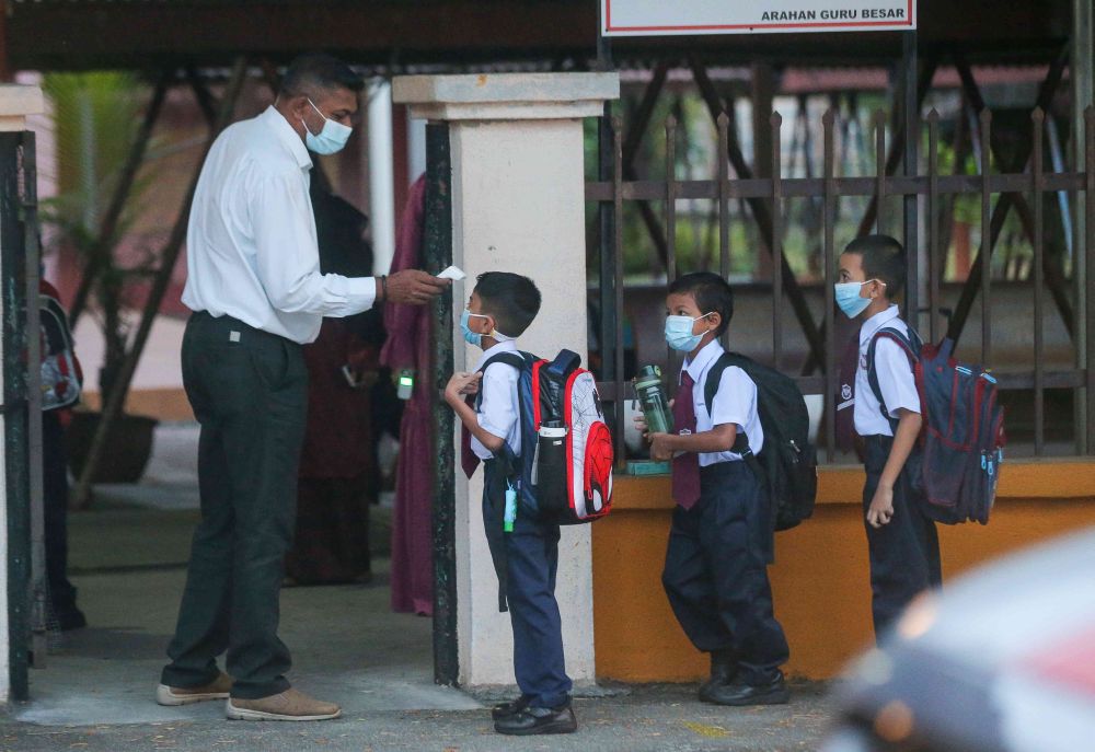 A student gets his temperature checked at Sekolah Kebangsaan Cator Avenue, Ipoh as schools reopen March 1, 2021. — Picture by Farhan Najib