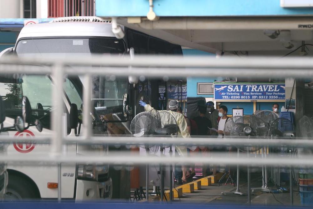 Foreign workers staying at Westlite Woodlands dormitory boarding a bus that will transport them to a government quarantine facility on April 22, 2021. — TODAY pic