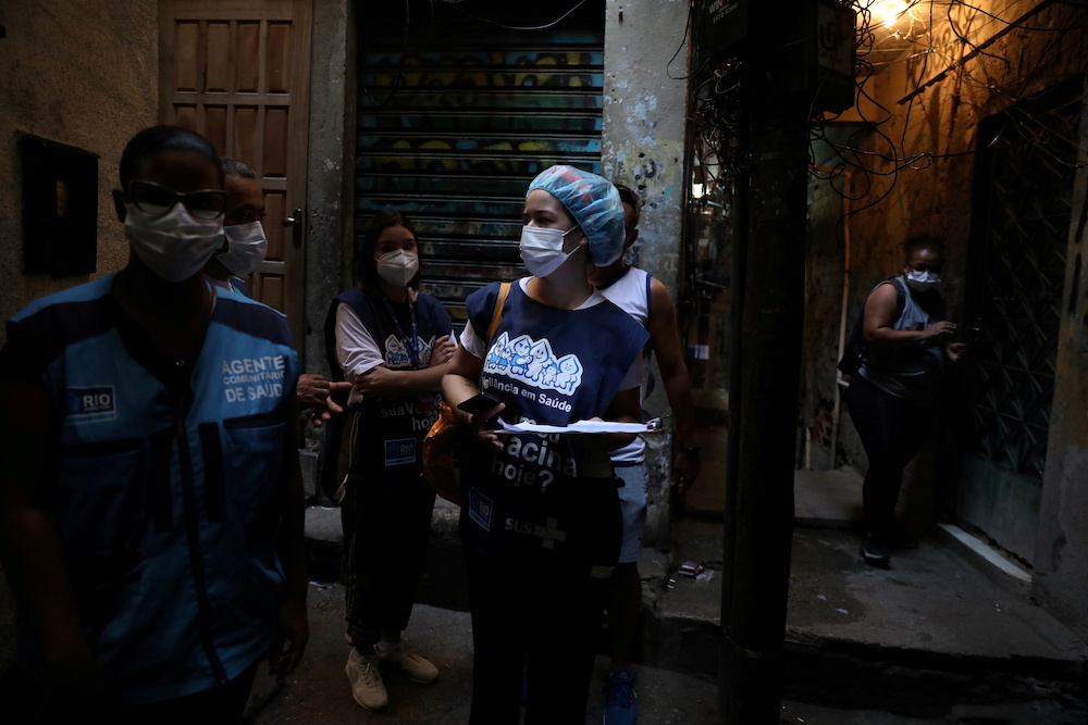 Health workers look for an address as they administer the coronavirus disease vaccine to elderlies who cannot leave home, in the Rocinha slum in Rio de Janeiro, Brazil April 16, 2021. — Reuters pic