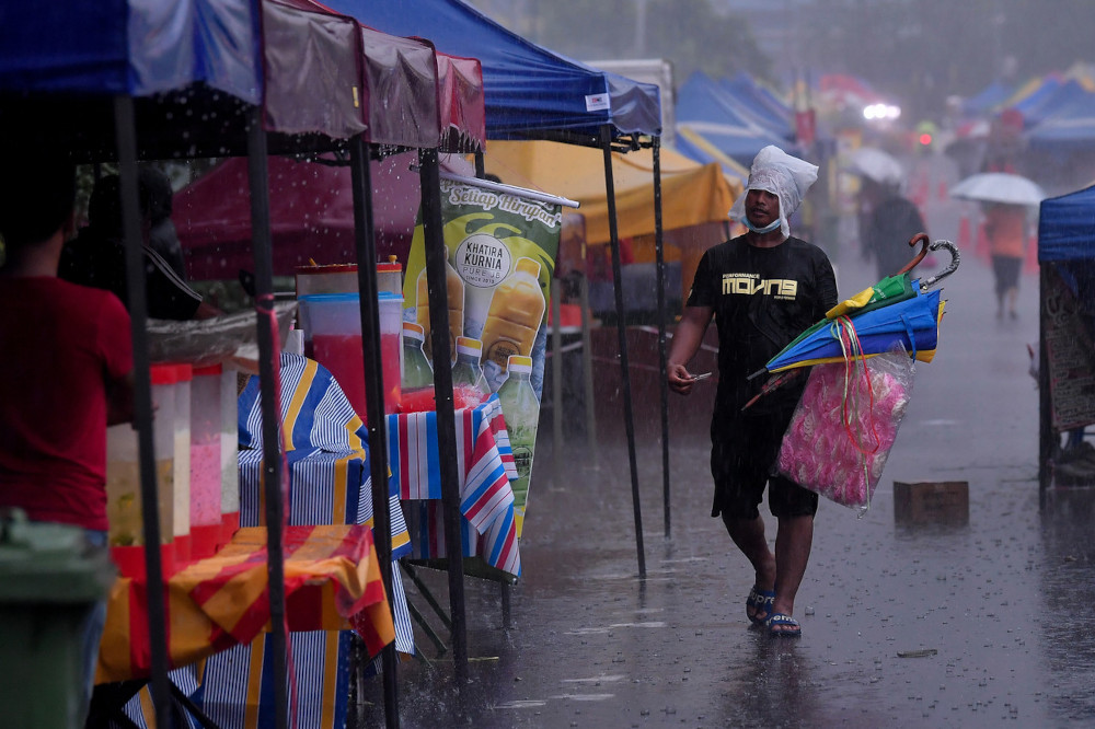 Despite the downpour, people can be seen buying food at the Kampung Baru Ramadan bazaar, April 13, 2021. — Bernama pic 