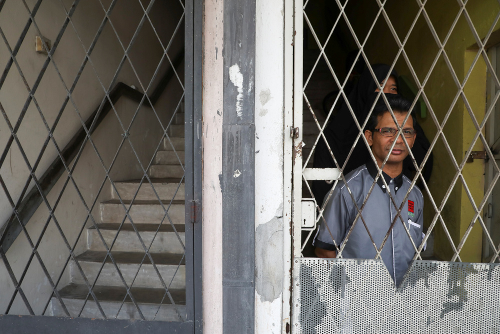 Rohingya refugee and activist Zafar Ahmad Abdul Ghani and his wife look out from their home in Kuala Lumpur, Malaysia March 19, 2021. Picture taken March 19, 2021. — Reuters pic