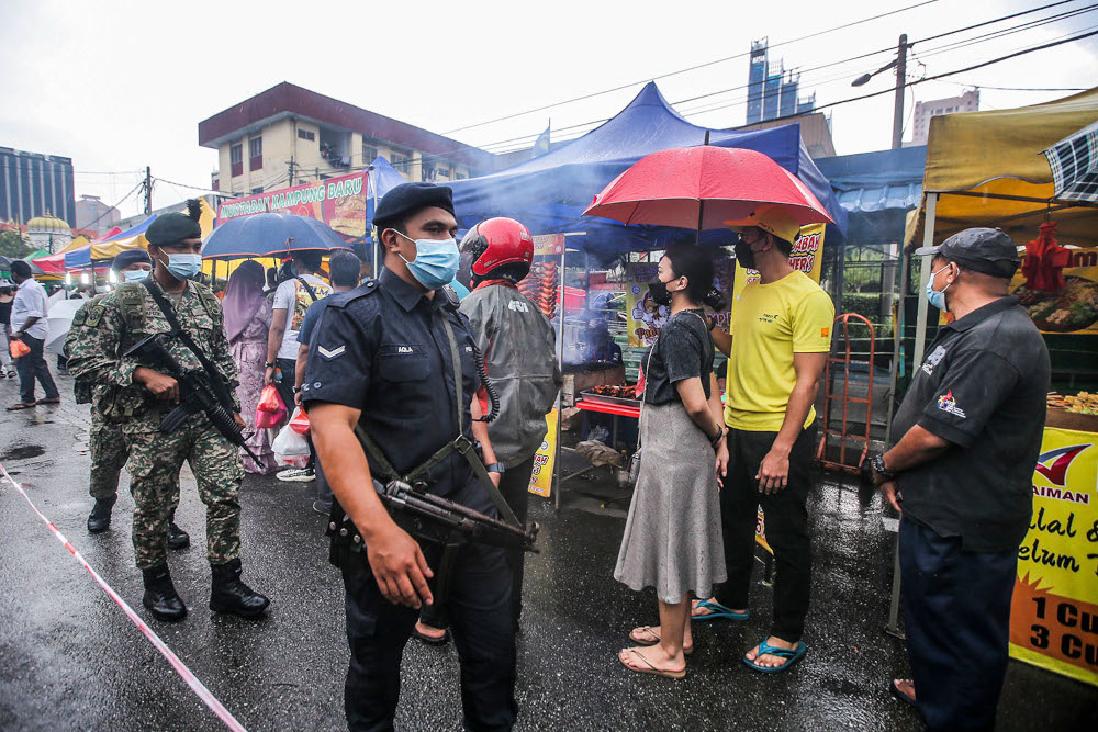 Police and army personnel observe visitors to ensure SOP compliance at the Kampung Baru Ramadan bazaar April 14, 2021. u00e2u20acu2022 Picture by Hari Anggara