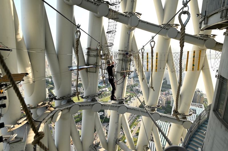 A guide crosses a section at the adventure park of Canton Tower in Guangzhou, China's southern Guangdong province. u00e2u20acu201d AFP pic