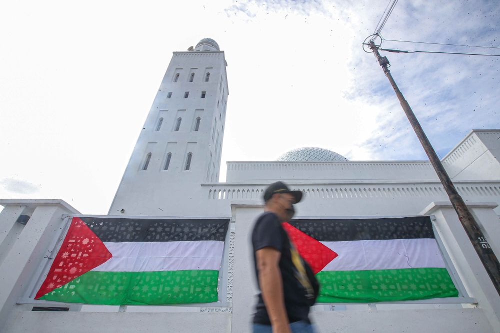 A man walks past Palestinian flags seen on the exterior walls of Masjid Jamek Idris Iskandar Shah in Ipoh on May 18, 2021. u00e2u20acu201d Picture by Farhan Najib