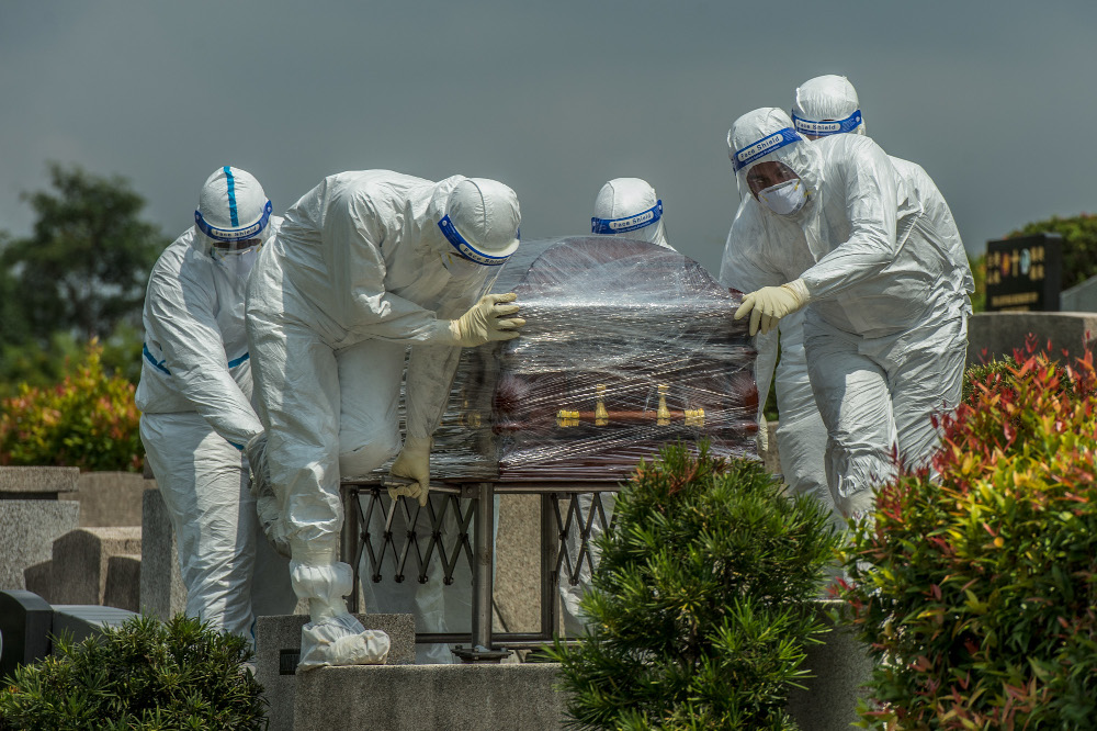 Workers in PPE suits carry the body of a person who died from the coronavirus disease (Covid-19) at a Christian cemetery in Semenyih, Selangor. — Picture by Shafwan Zaidon
