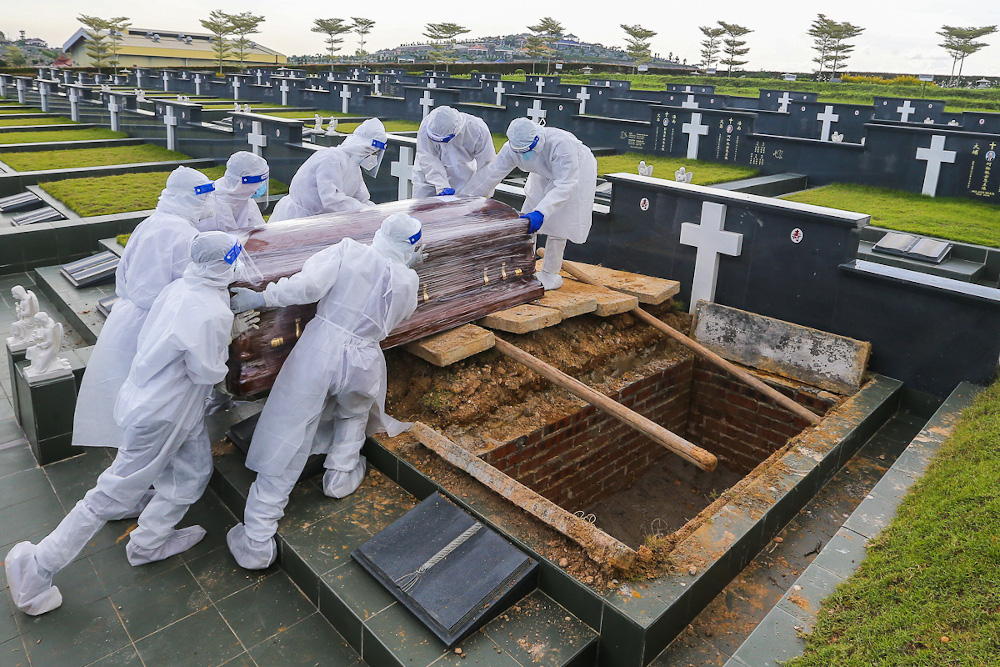 Workers wearing personal protective equipment (PPE) carry a coffin containing a body of a person who died from the Covid-19 disease at the Christian cemetery at Fairy Park in Klang June 6, 2021. u00e2u20acu201d Picture by Yusof Mat Isa