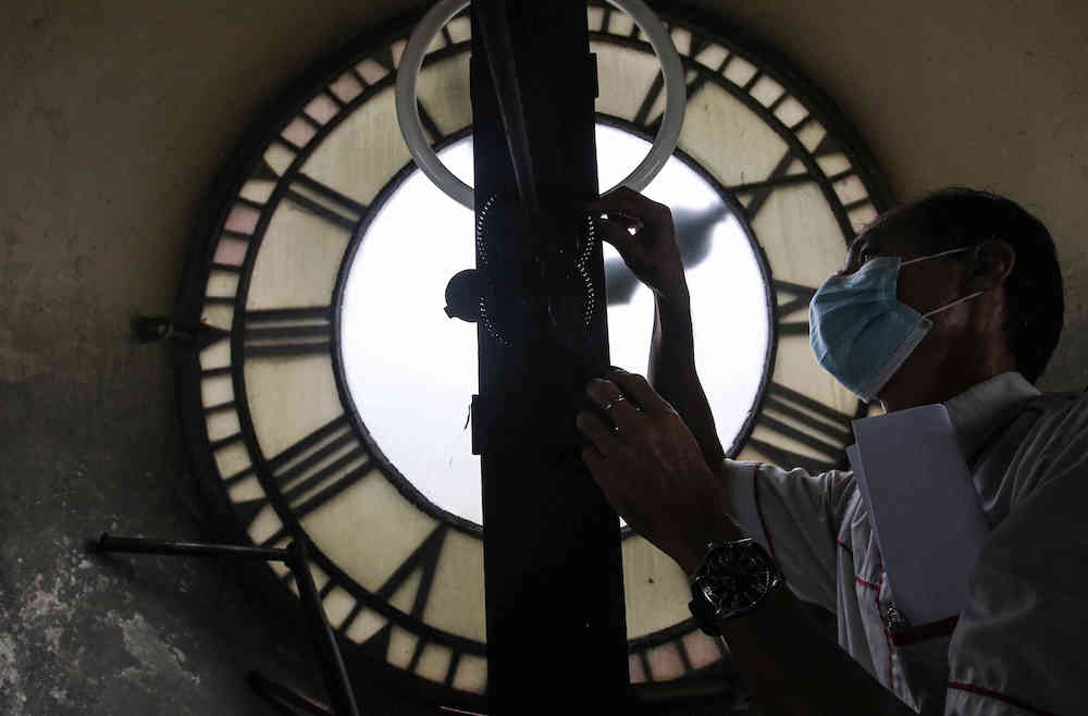 Time Recorder Sdn Bhd sales manager, Ui Foo Ming maintaining the clock tower, which has to be manually wound every five days. — Picture by Farhan Najib