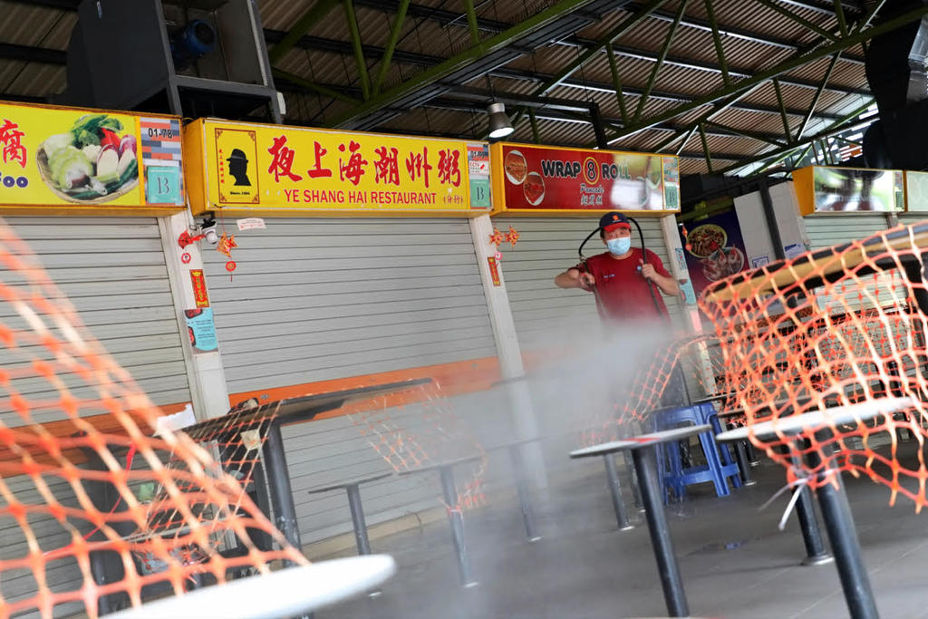 A cleaning worker is seen washing the tables at 115 Bukit Merah View Market and Food Centre on June 14, 2021 after a Covid-19 cluster emerged there. u00e2u20acu2022 TODAY pic