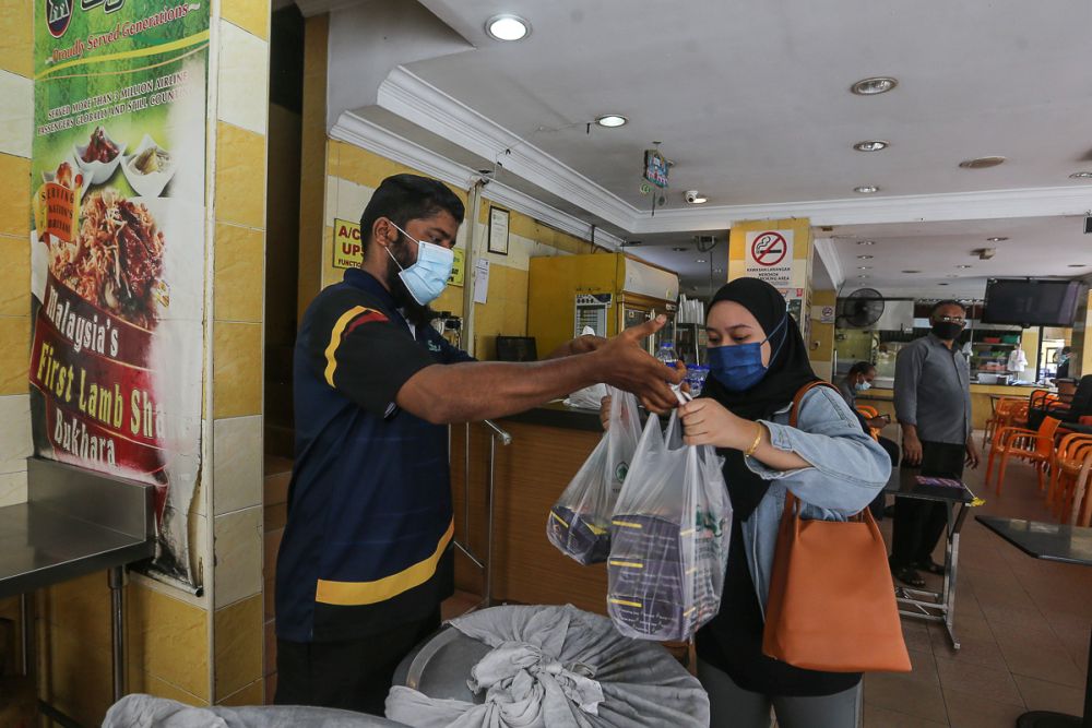 A patron packs food to go at Syed Bistro Restaurant in Puchong June 14, 2021. — Picture by Yusof Mat Isa