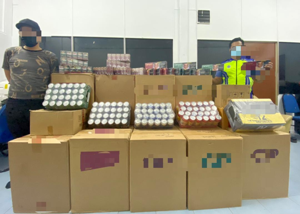 Region Two Marine Police Force personnel with the seized contraband cigarettes and alcohol at a premises in Taman Kempas, Johor Baru July 30, 2021. u00e2u20acu201d Picture courtesy of the Region Two Marine Police Forcenn