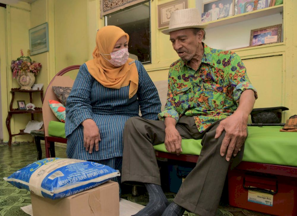 Johor Women, Family and Community exco, Zaiton Ismail (left) presenting a basket of food and money to veteran film actor and comedian, Abdul Rashid Yahya, better known as Mat Sentol at his home in Larkin April 20, 2021. u00e2u20acu201d Bernama pic