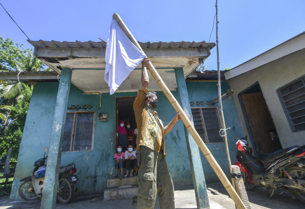 Zaidi Dollah, 56, hoisting a white flag in front of his house in Kampung Banggol, Gelang Mas, Kelantan, July 1, 2021. u00e2u20acu201d Bernama pic 