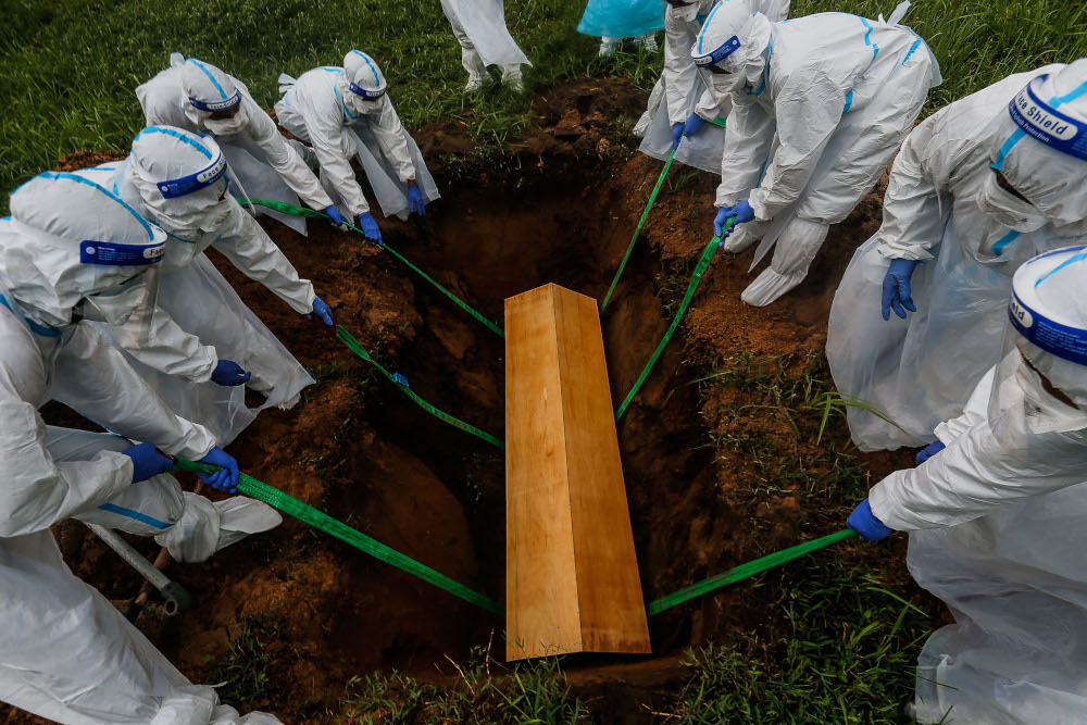 Volunteers lower the body of a Covid-19 victim in the grave for burial at Bagan Ajam Muslim Cemetery, August 24, 2021. u00e2u20acu201d Picture by Sayuti Zainudin