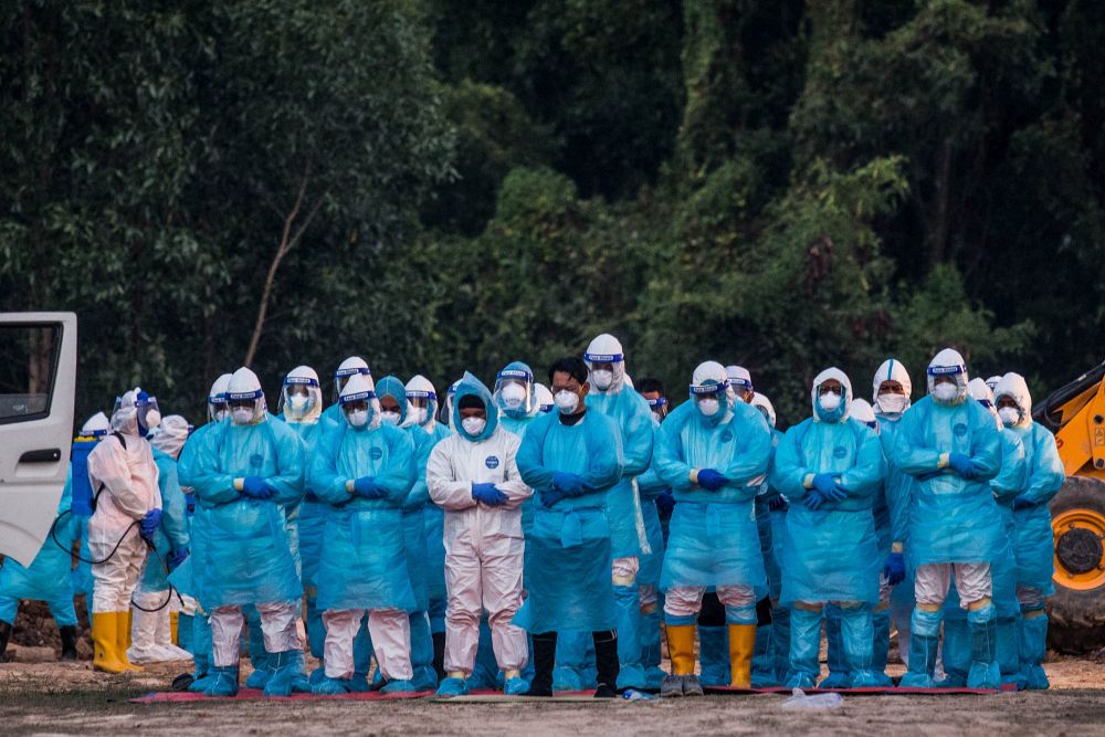 Funeral workers wearing protective suits perform Maghrib prayers before burying the remains of a Covid-19 victim at a cemetery in Klang August 7, 2021. u00e2u20acu201d Picture by Firdaus Latif