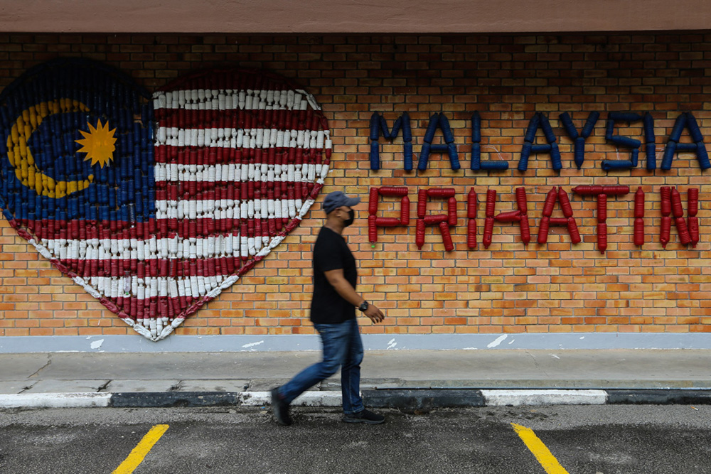 A man waks past a Malaysia Prihatin wall decoration in Kuala Lumpur August 25, 2021. u00e2u20acu201d Picture by Ahmad Zamzahuri