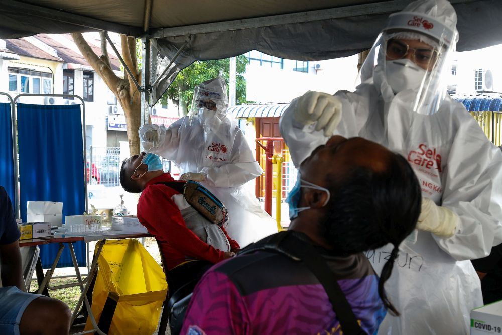 2021 年 8 月 12 日，在乔治市 Taman Manggis 的一次大规模筛查活动中，医护人员收集拭子样本以测试 Covid-19。 — 图片来自 Sayuti Zainudin