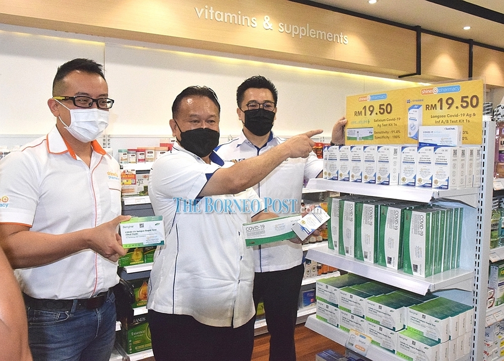 Nanta pointing to the price of RM19.50 per Covid-19 self-test kit which is lower than the ceiling price of RM19.90 set by the government. Also seen are Liew (left) and Tan. u00e2u20acu201d Picture by Roystein Emmor/Borneo Post