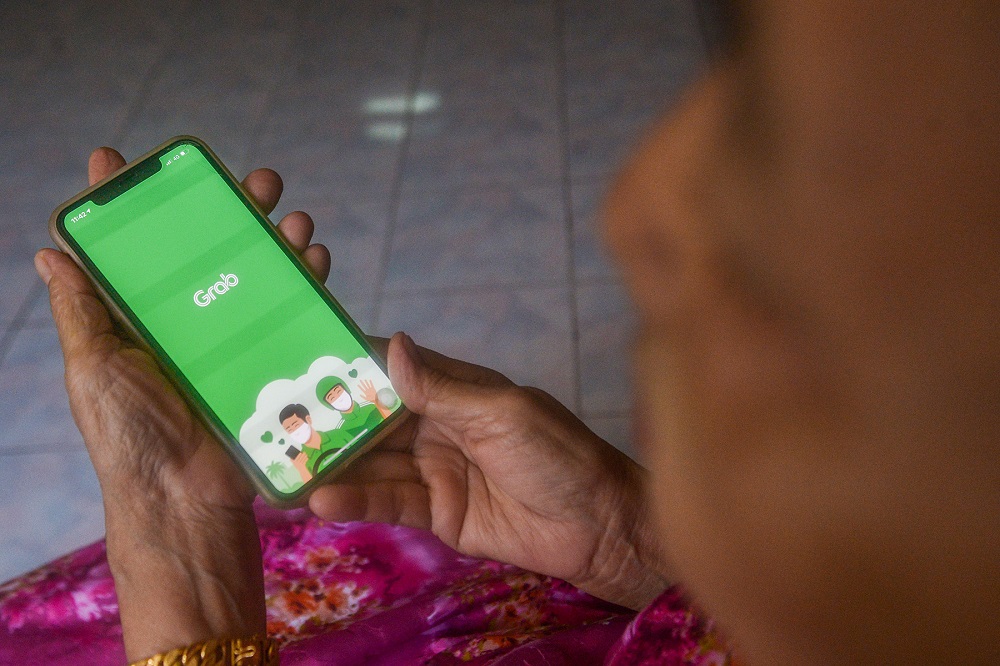 A woman launches the Grab app on her phone in Kuala Lumpur September 23, 2021. ― Picture by Miera Zulyana