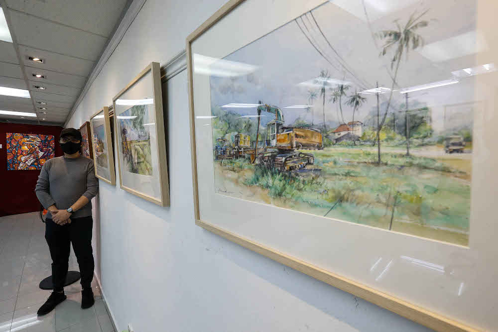 Vincent Phang poses for a photo with his paintings during an interview regarding his work being previewed here at The Art Gallery, Pulau Tikus October 15, 2021. 