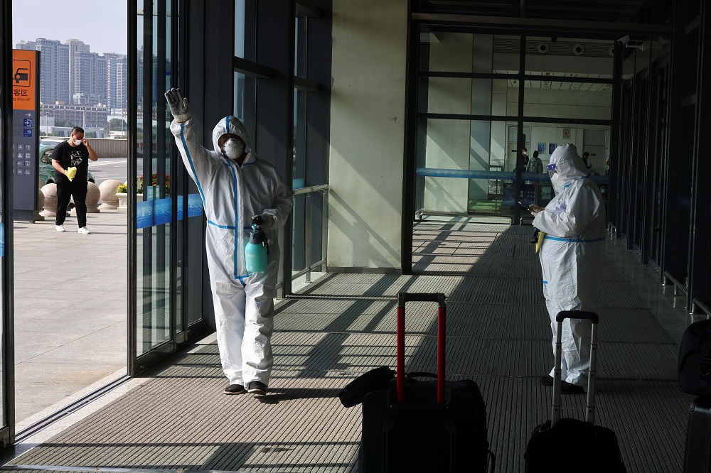 Staff members in protective suits, following the coronavirus disease outbreak, stand next to luggage at Dalian Railway Station in Dalian, Liaoning province, China September 29, 2021. u00e2u20acu2022 Reuters file pic