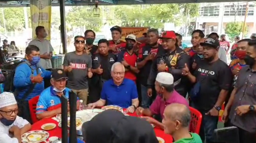 Datuk Seri Najib Razak shared a video in which he was seen having a meal surrounded by supporters at an open-air restaurant where many of the patrons were not observing social distancing and not wearing face masks. — Picture via Facebook/Najib Razak