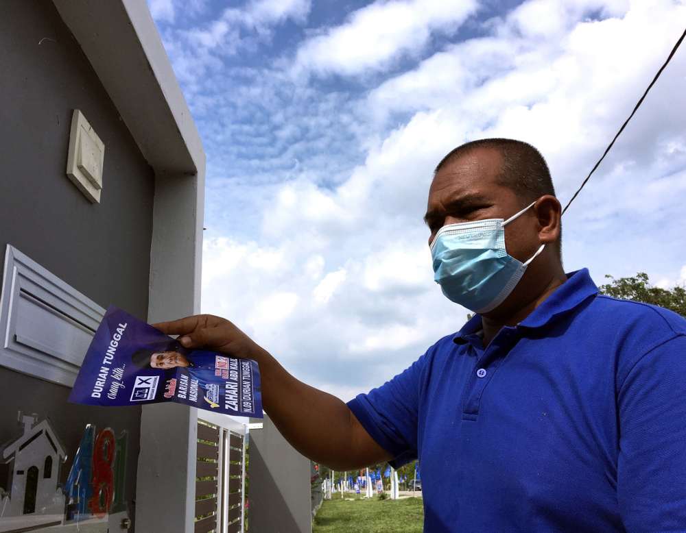 Barisan Nasional candidate Zahari Abd Kalil placing campaign leaflets in the mailbox of residents in Kampung Beringin, Jasin, November 16, 2021. u00e2u20acu201d Bernama pic 