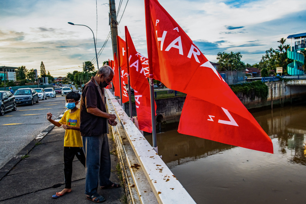 A Pakatan Harapan volunteer putting up PH flags at Jalan Klebang for the Melaka election, November 8, 2021. — Picture by Shafwan Zaidon