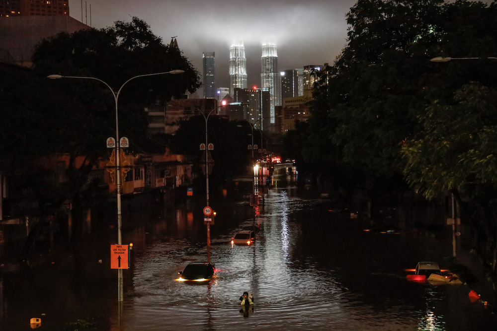 People walk through floodwaters on Jalan Sultan Azlan Shah in Kuala Lumpur amid incessant rain, December 19, 2021. u00e2u20acu201d Picture by Firdaus Latif