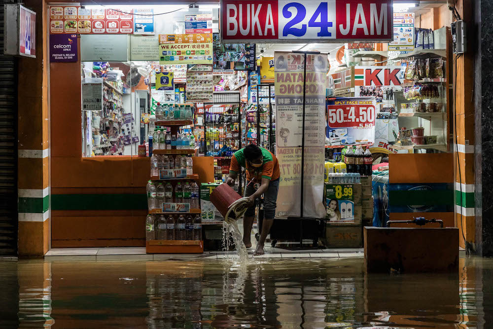 A worker cleans the floor after incessant rain caused floods in Kuala Lumpur December 19, 2021. — Picture by Firdaus Latif 