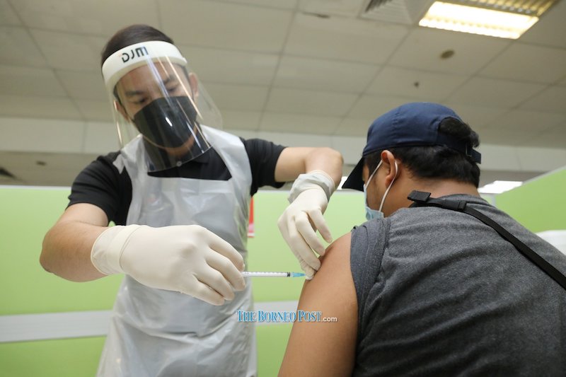 A health worker administering the Covid-19 vaccine jab on a vaccine at the Longi Industrial PPV in Kuching, in this photo taken on September 5, 2021. — Picture by Chimon Upon via Borneo Post