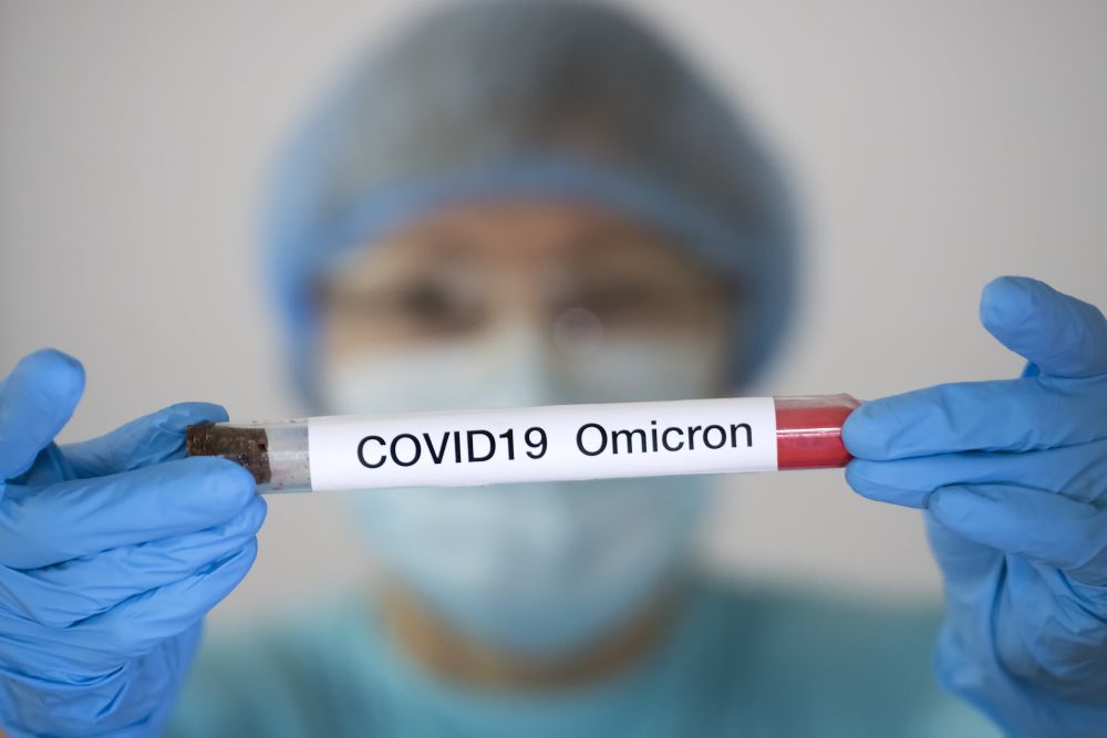 身着防护服和面罩的妇女拿着试管，分析样本怀疑在 2021 年 12 月 1 日感染了 Omicron 冠状病毒变种。 —路透社图片