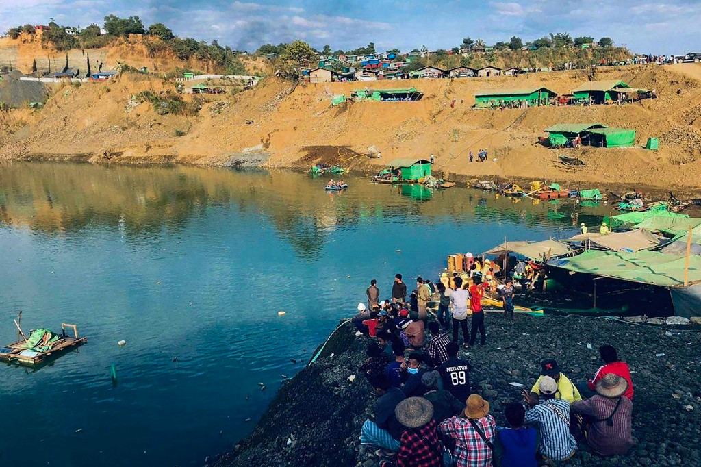 This photo taken and received via an anonymous source on December 22, 2021 shows onlookers watching as rescue officials search for missing people after a landslide at a jade mine in Hpakant, Kachin state. — Handout via AFP