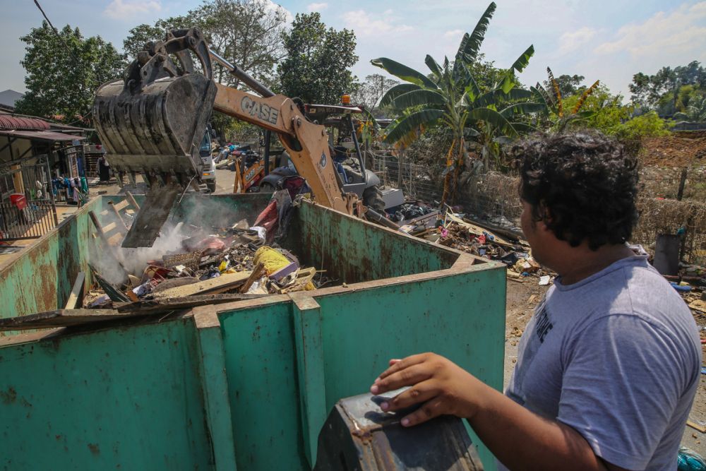 A man looks on as an excavator clears debris and rubbish off the streets in Taman Sri Muda, Shah Alam December 29, 2021. u00e2u20acu201d Picture by Yusof Mat Isa