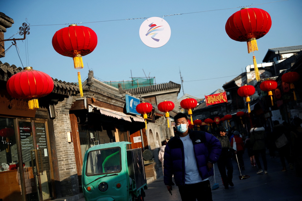 A man walks at a hutong alley decorated with lanterns and a sign of the Beijing 2022 Winter Olympics, ahead of the opening ceremony of the Games and the Chinese Lunar New Year holiday, in Beijing, China January 29, 2022. — Reuters pic
