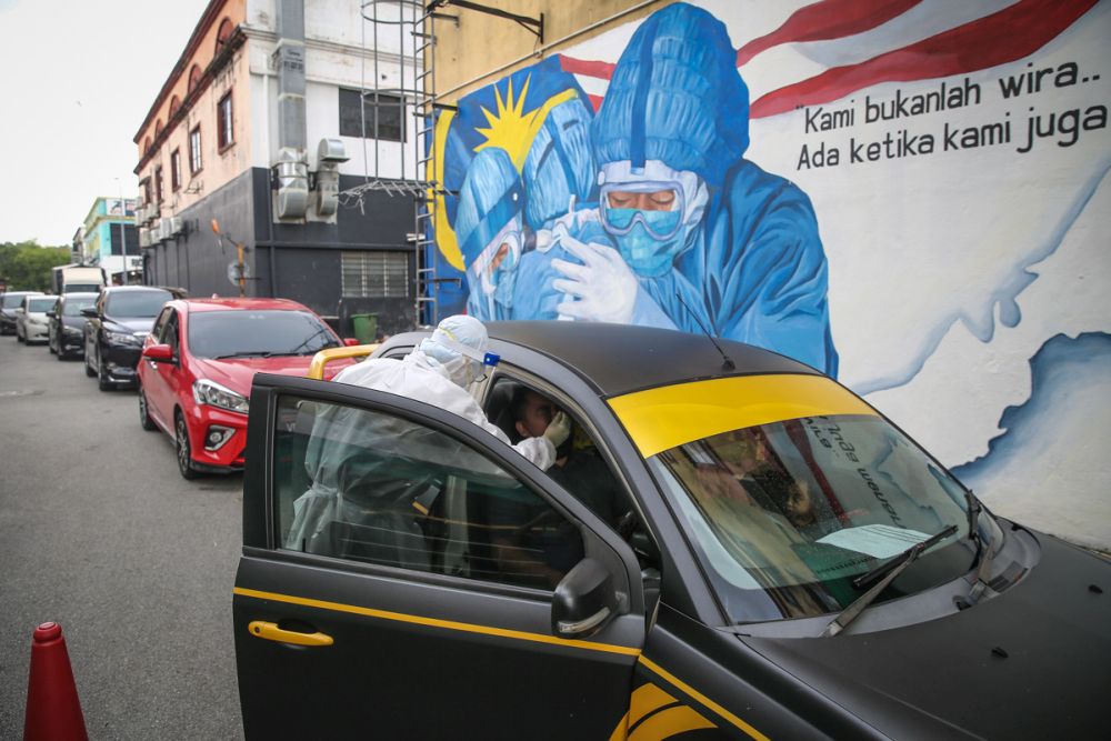 A health worker in protective suit collects swab samples from a motorist at a drive-through testing site for Covid-19 at Ajwa Clinic in Shah Alam February 9, 2022. u00e2u20acu201d Picture by Yusof Mat Isa