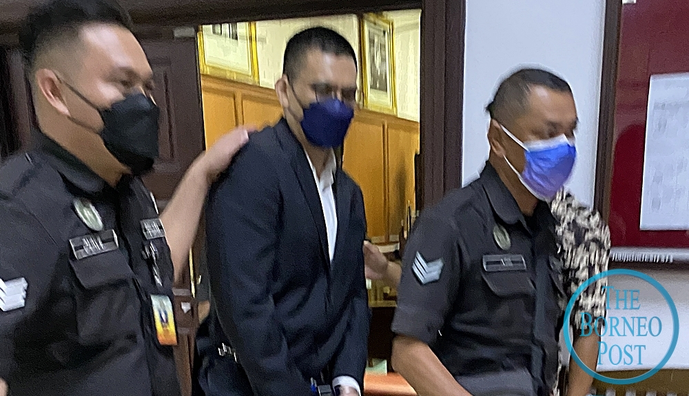 Mohamad Fitri (centre) is escorted out of the courtroom after the case proceedings March 15, 2022. u00e2u20acu201d Borneo Post pic