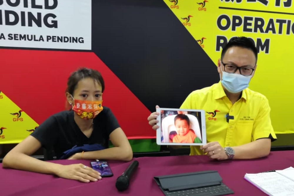 SUPP Youth secretary-general Milton Foo holds up the missing child’s photo during the press conference. Seated next to him is the boy’s mother. — Borneo Post pic