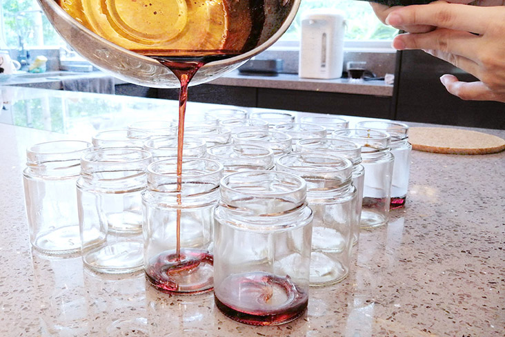 Pouring caramel into the glass jars first.