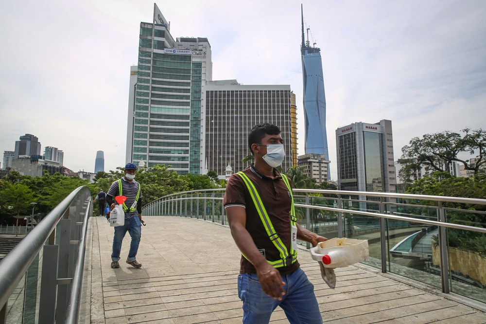 People wearing protective face masks walk along the Jamek Mosque Pedestrian Bridge in Kuala Lumpur March 4, 2022. ― Picture by Yusof Mat Isa